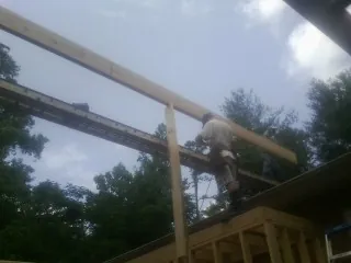 Carpenter setting a ridge beam over a new addition frame — Ice Dam Removal by Roofing Brothers in Naples