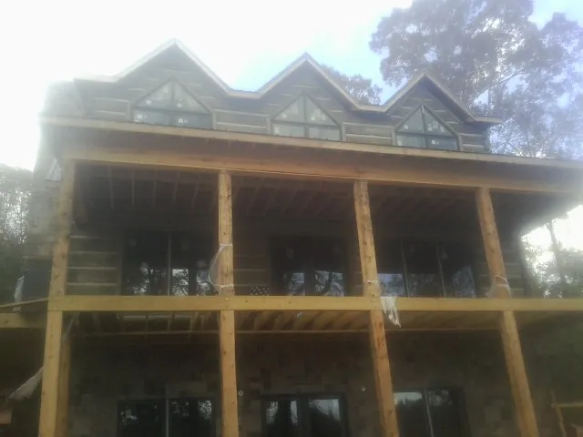 Dormers and porch framing on a large log home under construction — Roof Coating work by our crew in Naples