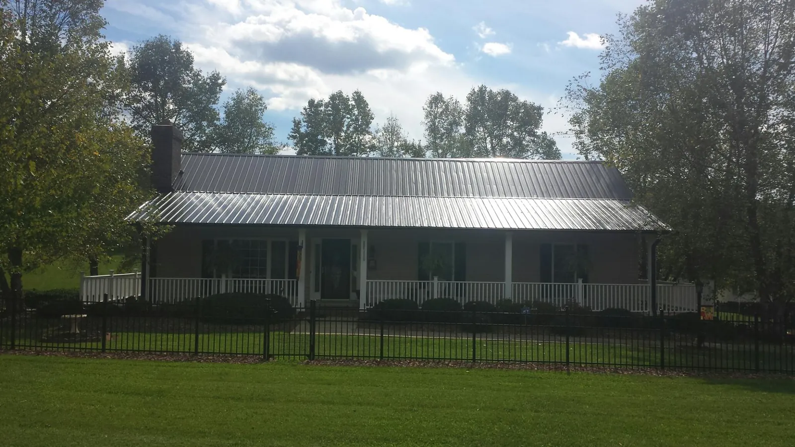 Gray metal roof on a brick ranch with a full width front porch — Gutter Guard Installation work by our crew in Naples