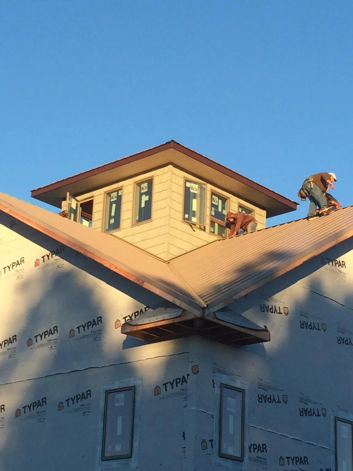 Roofers working around a rooftop cupola on a new metal roof at sunset — Roof Waterproofing in Naples by Roofing Brothers